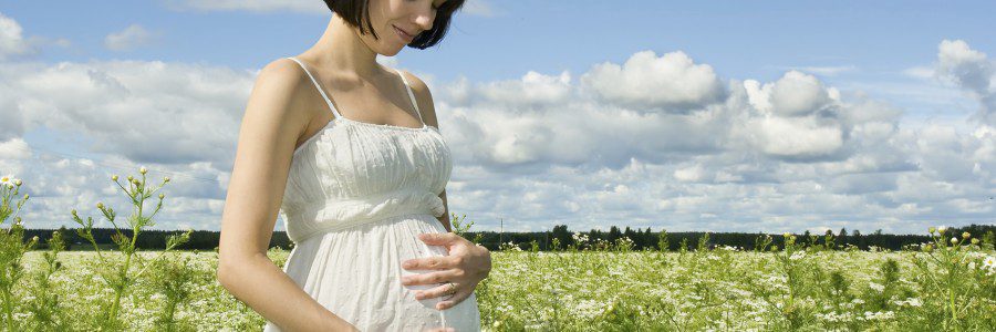 Pregnant woman smiling on a field